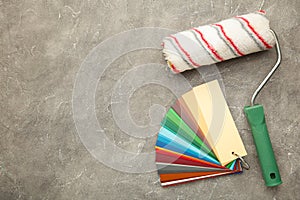 Paint roller brush and color palette guide on grey concrete background. Close up view