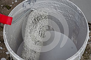 paint roller in a bucket with gray paint