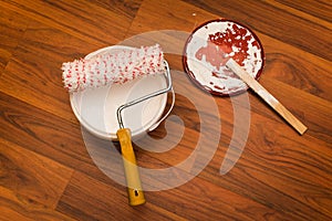 Paint roller on the bucket of white  wall paint stay on the wooden parquet floor, bird eye view, isolated.