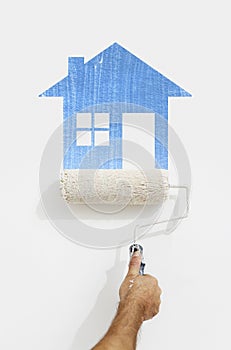 Paint roller hand with blue house symbol painting on wall