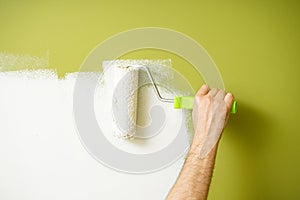Paint roller in the hand of a man repainting the wall. Painting work