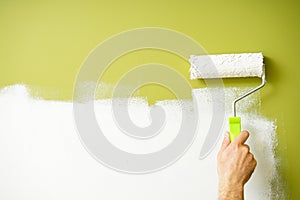 Paint roller in the hand of a man repainting the wall, space for text