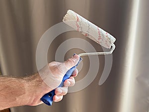 Paint roller in the hands of a man
