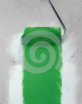 Paint roller leaving stroke of brown green over a white