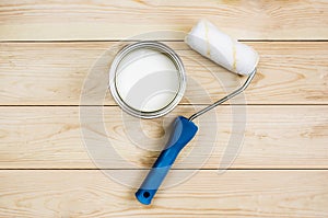 Paint roller with paint in the pot on wooden boards