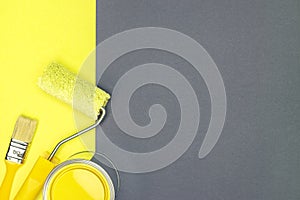 Paint roller, paintbrush and can with yellow paint on yellow and gray background. home renovation tools.
