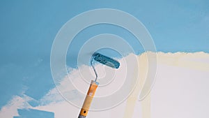 Paint roller painting wall with blue color, white copy space for text.