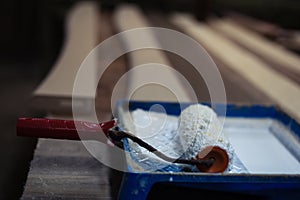 Paint roller soiled with white paint in a blue container