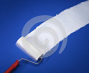 Paint roller with white paint on blue wall