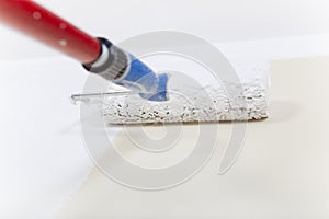 Paint roller with white paint on wall