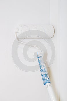 Paint roller on white wall. Renovation of paint on the wall. Vertical image.