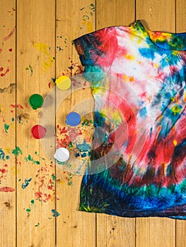 A paint-stained wooden table with a tie dye t-shirt. Flat lay.