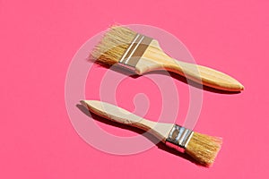 Paint varnishing brushes with wooden handle on trendy fuchsia pink background. Interior design home refurbishing fashion concept