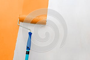 Paint the walls with a roller. Painting works. Orange paint, white wall.