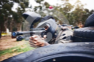 Paintball, gun or man playing a shooting game with fast action on a fun battlefield on holiday. Military mission