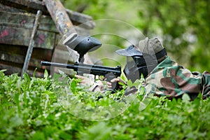 Paintball player in camouflage lies in ambush photo