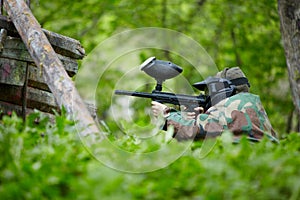 Paintball player in camouflage sits in ambush