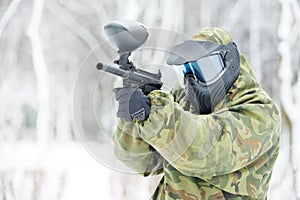 Paintball player with marker at winter outdoors