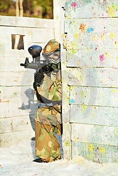Paintball player with marker at winter outdoors