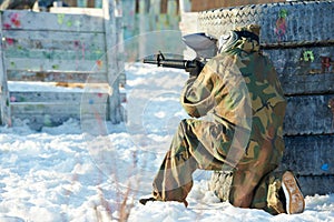 Paintball player with marker at winter outdoors