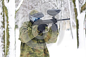 Paintball player with marker at winter outdoors