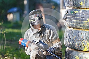 Paintball player with paint gun sitting behind fortification