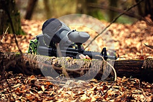 Paintball player in protective uniform and mask aiming gun in th