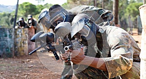 Paintball players aiming and shooting with guns at opposing team outdoors