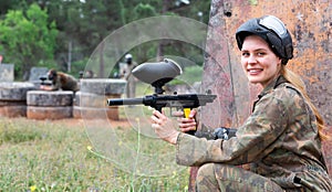 Paintball players of one team in camouflages and masks aiming with gun in shootout playing