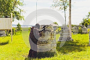 Paintball sport player in protective uniform and mask playing with gun outdoors.