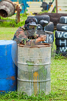 Paintball sport player in protective uniform and mask playing wi