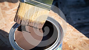 Paintbrush in the can of brown paint