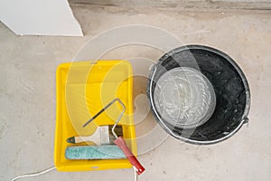 Paintbrush, roller and glue container on concrete surface. Composition tools for home repair and interior renovation