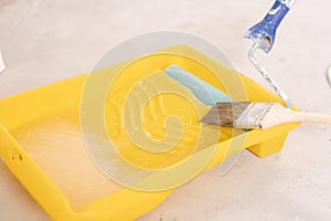 Paintbrush, roller and glue container on concrete surface. Composition tools for home repair and interior renovation