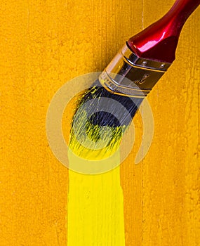 Paintbrush with yellow paint dye wooden wall