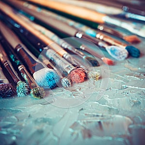 Paintbrushes on artist canvas covered with oil paints