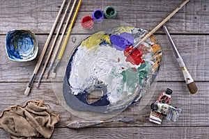 Paintbrushes, artist palette, oil paints on desk in painter studio. Close up