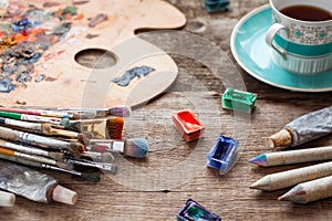 Paintbrushes, artist palette, pencils, coffee cup and paints