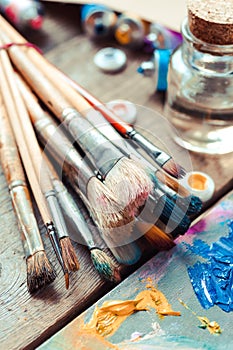 Paintbrushes closeup, artist palette and multicolor paint tubes. photo