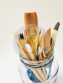 Paintbrushes in a glass jar isolated on grey background. vertical.