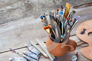 Paintbrushes in a jug from potters clay, palette and paint tubes