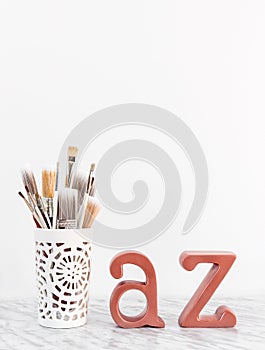 Paintbrushes with metal A and Z letters on marble surface