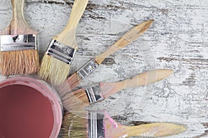 Paintbrushes and paint can in a wood background