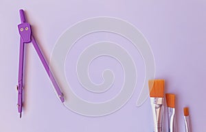 Paintbrushes and the purple metal callipers on a purple surface