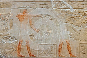 painted ancient limestone Egyptian relief of human figures doing trades and hieroglyphs