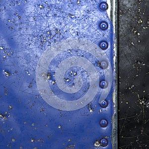 Painted blue metal with rivets on black metal background. 3d