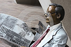 Painted bronze statue of a man reading a newspaper