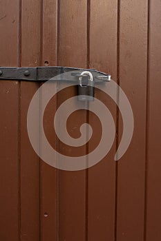 Painted brown door with a hanging iron lock outdoor