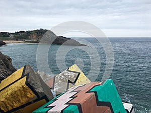 Painted cement breakwater blocks on the coast of Llanes