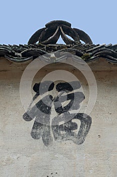 A painted Chinese character expressing good luck and good fortune painted on a wall fades